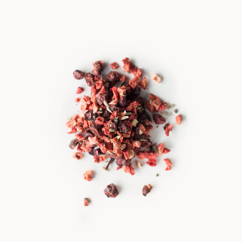 A pile of dried, finely chopped red fruit pieces, aptly named Schisandra Berry Blush from Rishi Tea & Botanicals, against a white background.
