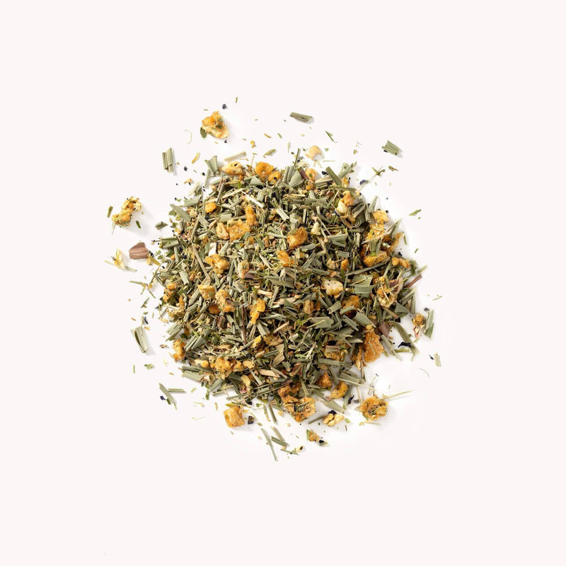 A pile of Blue Meadow by Rishi Tea & Botanicals, including chamomile blossoms, lemongrass, and various green leaves, scattered on a white background.